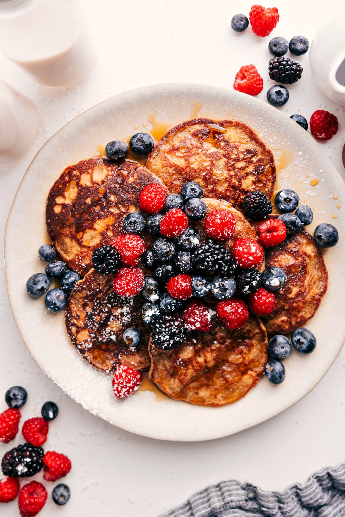 Plateful of Healthy Pancake Recipe That Always Is A Hit Healthy Pancake Recipe topped with berries, syrup, and powdered sugar.