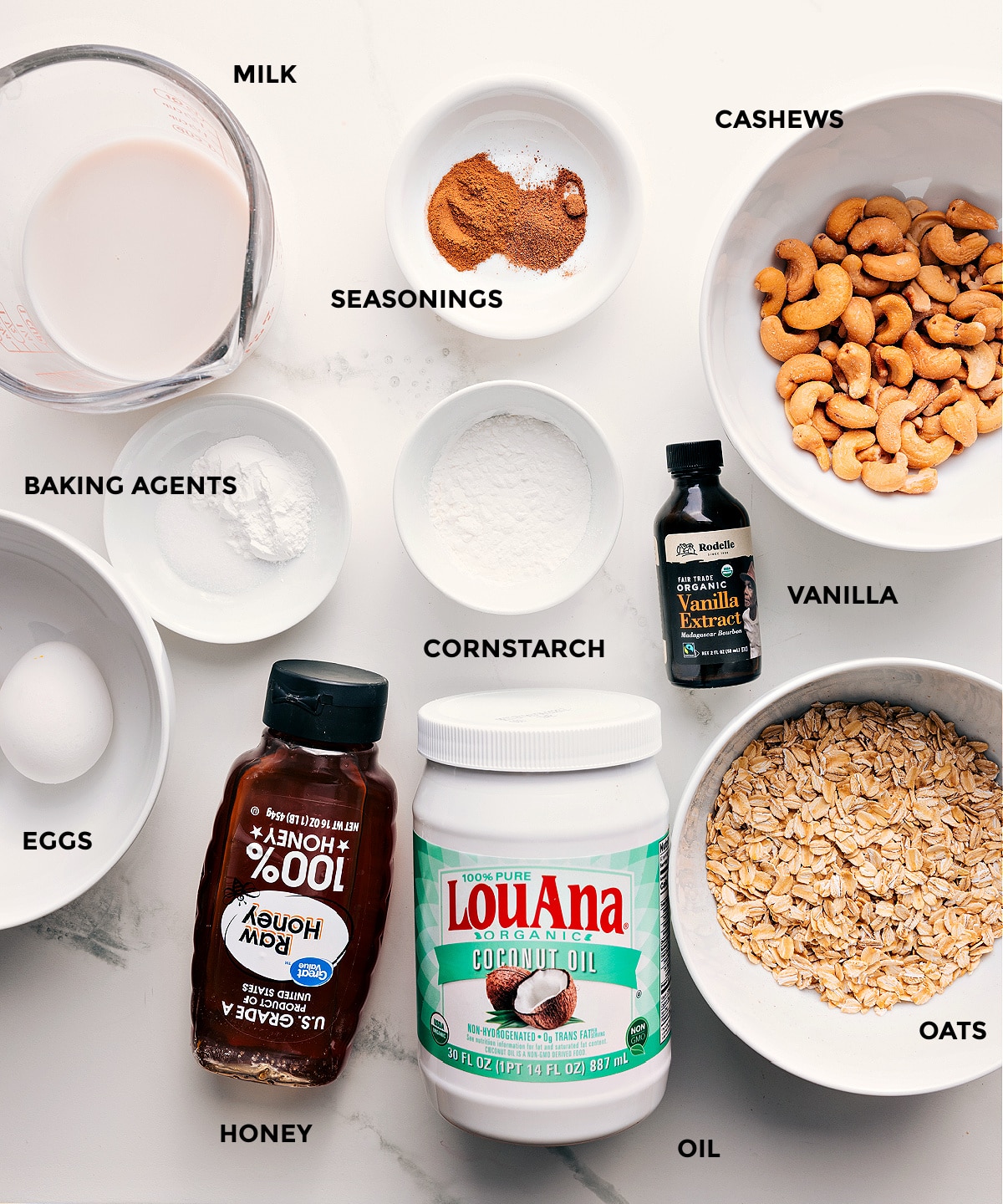Ingredients In Healthy Pancake Recipe All the ingredients in this recipe prepped out for easy assembly including milk, seasonings, cashews, vanilla, cornstarch, baking agents, oats, coconut oil, honey, and eggs.