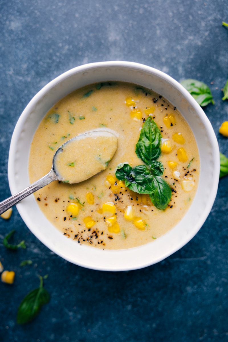 A fresh and vibrant Corn Soup with sweet corn and fresh basil requires minimal ingredients and a quick prep time. You'll be amazed how much flavor can come from so few ingredients! This soup is a naturally dairy-free and gluten-free meal. Recipe via ChelseasMessyApron.com #soup #corn #vegetarian #dairyfree #glutenfree #summertime Corn Soup in a bowl with a spoonful coming out.