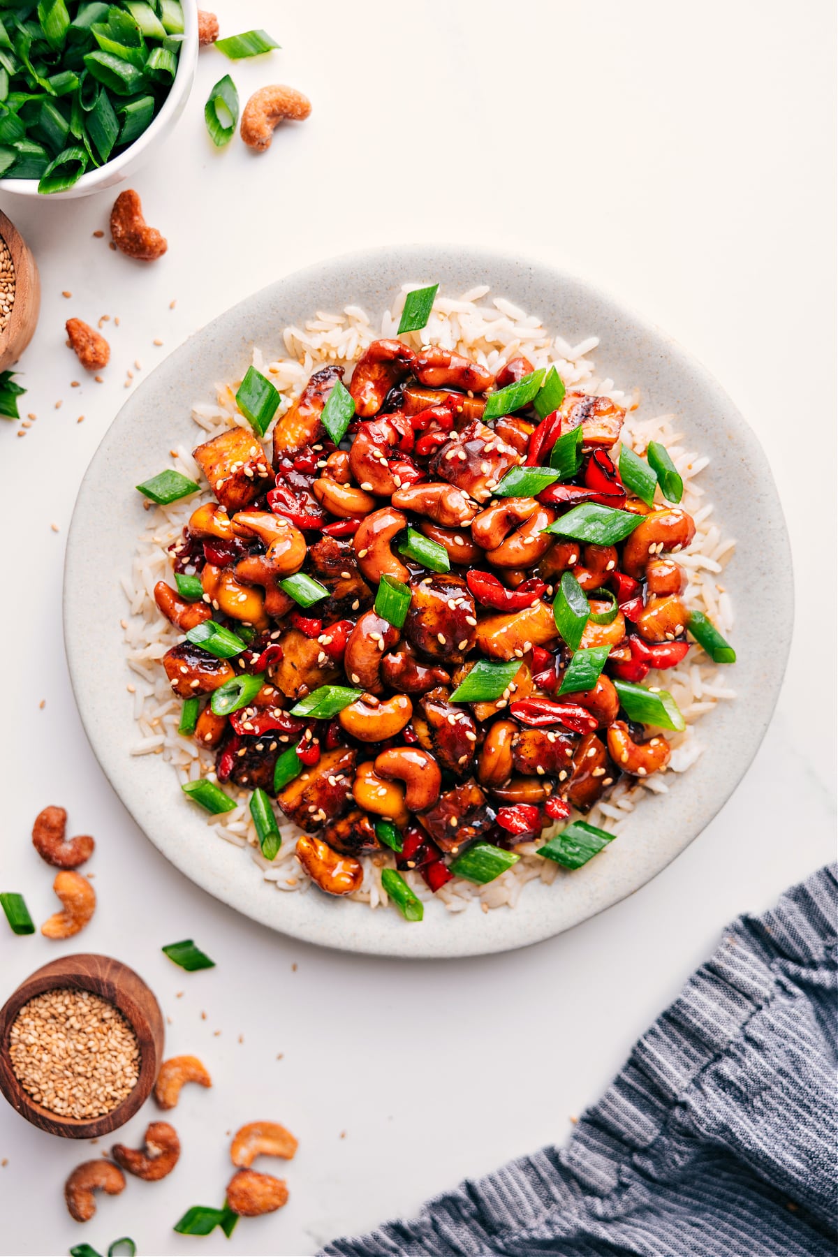 Super Simple And Delicious Cashew Chicken Recipe Cashew Chicken Recipe over rice with fresh green onions and sesame seeds on top.