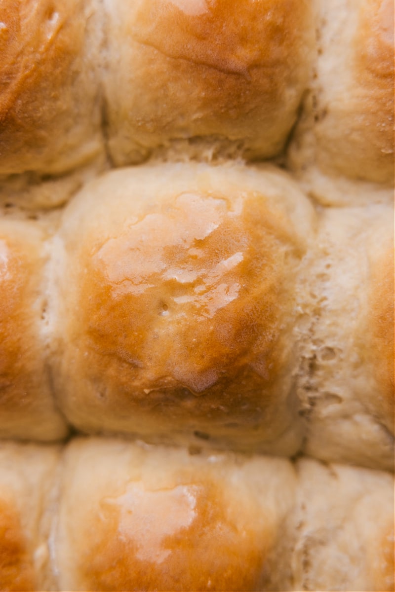 Delicious dinner rolls are made easy with NO stand mixer, no hand mixer, and no kneading required! These rolls rise high with big soft centers and perfectly crisp edges. Yes, really, these rolls are life-changing! Recipe via chelseasmessyapron #appetizer #familyfriendly #noknead #thanksgiving #best #easy #simple #kidfriendly #dinner #rolls Up-close overhead image of Life-Changing No-Knead Dinner Rolls