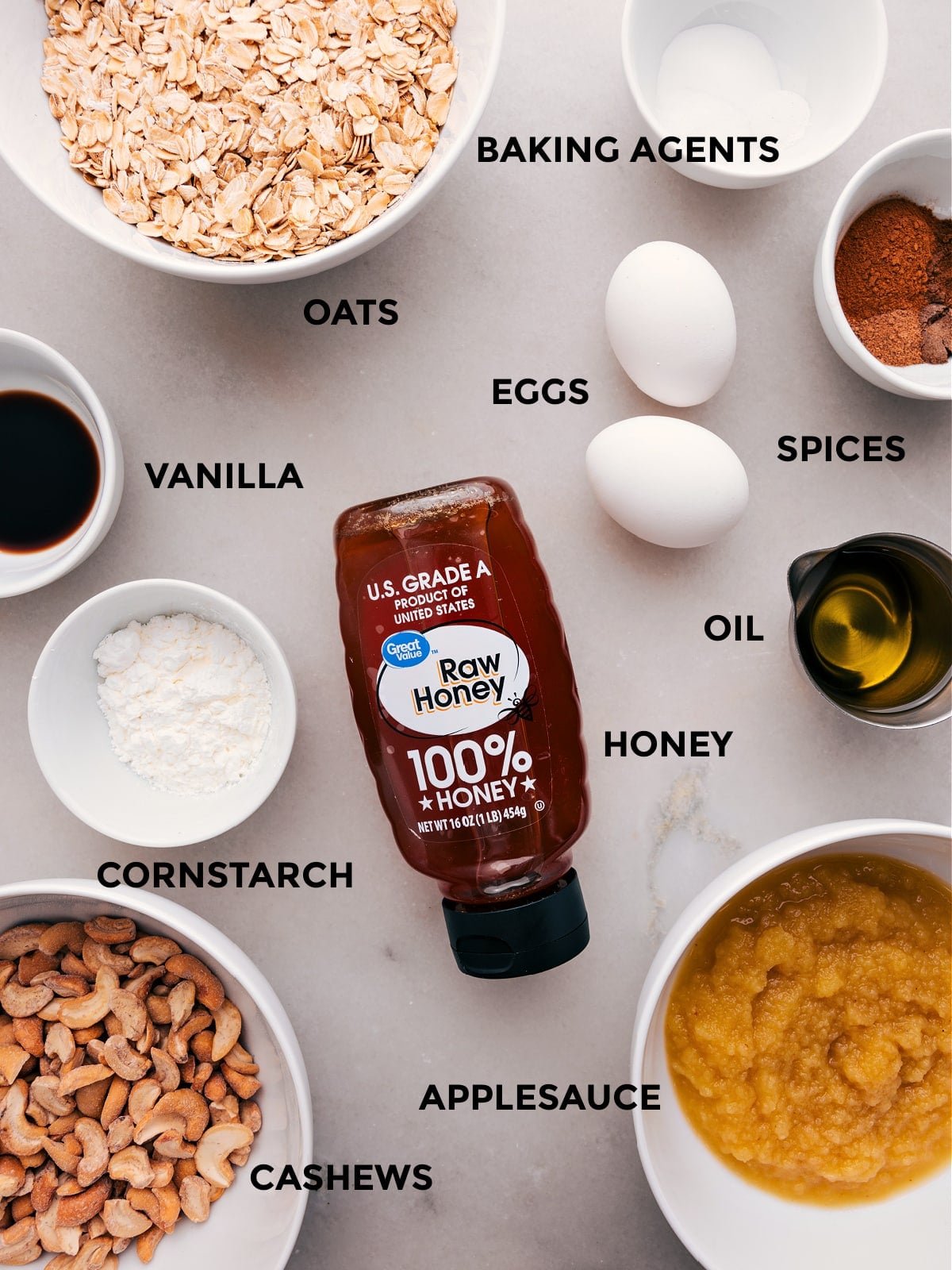 Ingredients In Healthy Apple Cake Prep all the ingredients for this recipe, including oats, baking agents, eggs, spices, oil, honey, vanilla, cornstarch, cashews, and applesauce, for easy assembly.