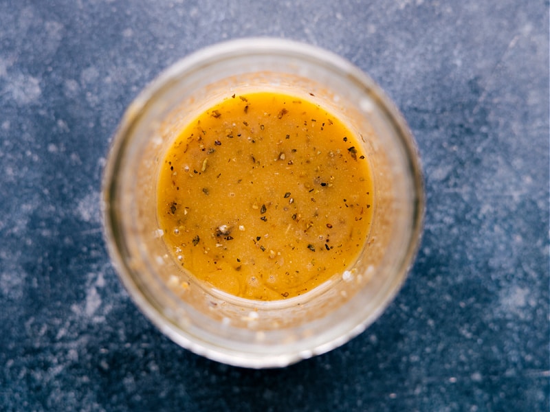 This simple Vinaigrette is a kitchen staple! Whip up a batch at the beginning of the week and drizzle it on salads, roasted veggies, or use as a quick sauce for fish or grilled chicken -- the applications are practically endless. Nothing tastes better than a homemade dressing, and this one is the best! Recipe via ChelseasMessyApron.com #vinaigrette #salads #dressing #homemade #herbs #vinegar #oliveoil Overhead view of Vinaigrette in a cruet