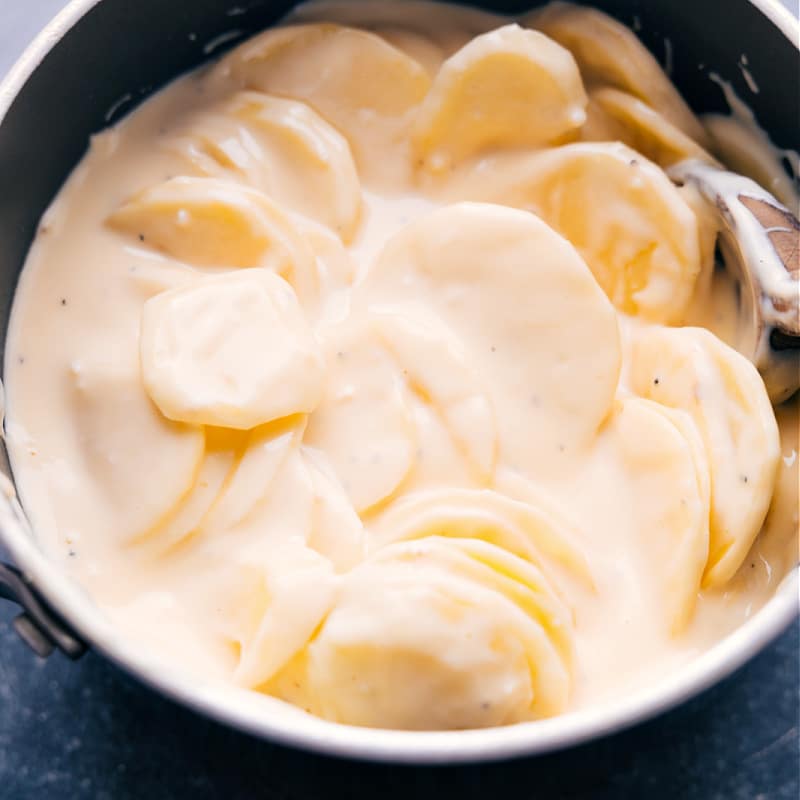 Crockpot Au Gratin Potatoes are pure comfort food and these are the BEST! Thinly sliced potatoes in an ultra-cheesy cream sauce are slow cooked to tender perfection. Save that precious oven space during the holidays OR prepare these in the summer while keeping the oven off and the heat out of the kitchen! Recipe via chelseasmessyapron #dinner #quick #easy #simple #healthy #best #thanksgiving #familyfriendly #crockpot #augratin #potatoes Up-close overhead image of the dish in the pot
