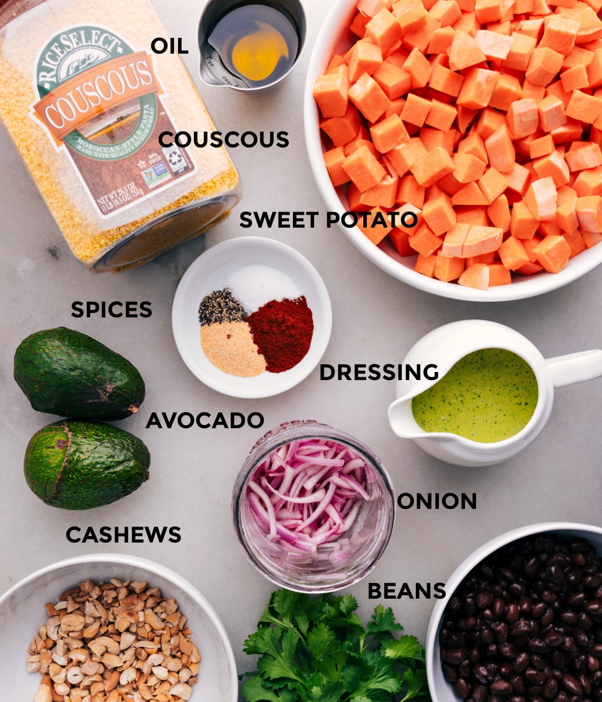 Ingredients In Sweet Potato Black Bean Salad All the ingredients for this recipe are prepped and ready for easy assembly, including sweet potatoes, couscous, dressing, onion, avocado, cashews, and black beans.