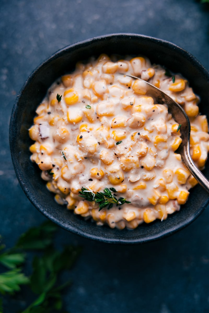 Our favorite Creamed Corn recipe complete with loads of sweet corn, smoky bacon, and the best savory Parmesan cream sauce. Recipe via chelseasmessyapron #sidedish #thanksgiving #best #familyfriendly #comfortfood #creamy #creamed #corn Overhead image of the side dish in a bowl