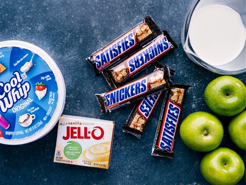 Snickers Salad is a retro-fluff salad combining diced Snickers bars and chopped apples in a creamy vanilla pudding and whipped topping mixture. Recipe via chelseasmessyapron #dessert #best #quick #easy #simple #familyfriendly #thanksgiving #treat #snickers #salad Ingredient shot-- image of all the ingredients used in this dish