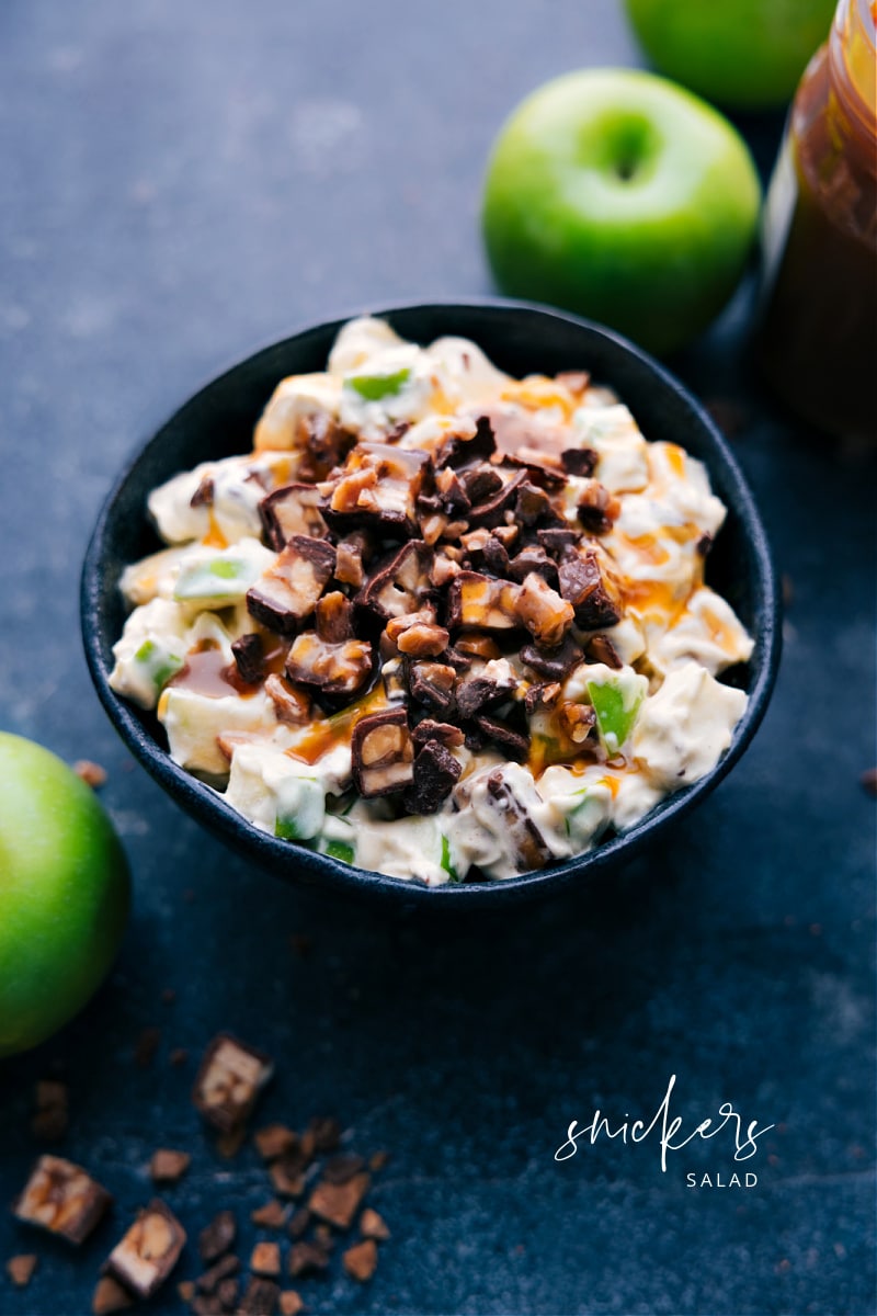 Snickers Salad is a retro-fluff salad combining diced Snickers bars and chopped apples in a creamy vanilla pudding and whipped topping mixture. Yes--it's not really a "salad," but a fun dessert! Recipe via chelseasmessyapron #dessert #best #quick #easy #simple #familyfriendly #thanksgiving #treat #snickers #salad Image of Snickers Salad