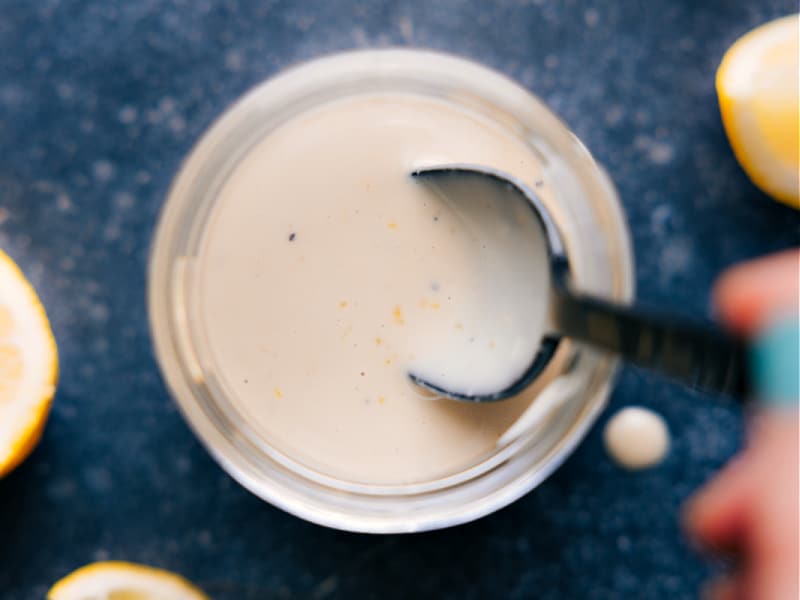 This Tahini Dressing is luxuriously thick and creamy! It's delightfully flavored with a hint of lemon and touch of honey. Drizzle this dressing on your favorite salad. Recipe via chelseasmessyapron #salad #saladdressing #tahini #dressing Overhead image of Tahini Dressing ready to be enjoyed