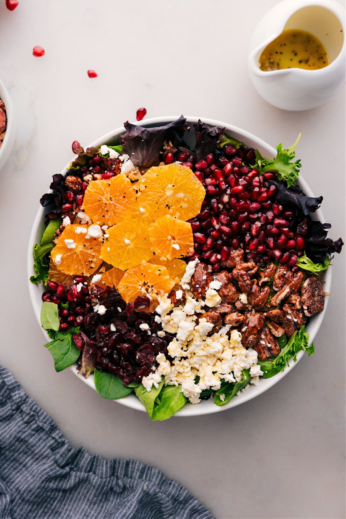 Winter Salad with ingredients tossed together, then topped with oranges, feta, nuts, pomegranates, and dried cranberries.