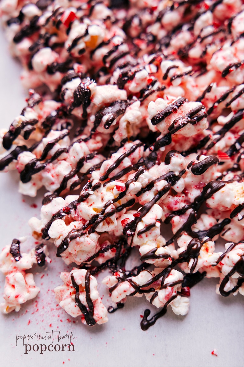 Peppermint Popcorn is a treat you won't want to miss this holiday season! Toss popcorn in white chocolate and crushed peppermint; then finish with a chocolate drizzle. This sweet snack mixย is nothing short of addicting!ย Recipe via chelseasmessyapron #dessert #best #quick #easy #simple #christmas #snackmix #holiday #holidaytreats #chocolate #peppermint #popcorn Overhead image of the snack ready to be enjoyed