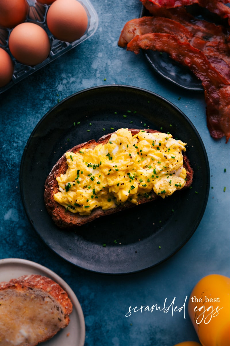 This recipe for Scrambled Eggs will elevate your breakfast game with its easy to follow steps, simple ingredients, and a technique that guarantees a delicious, creamy, and custardy pile of eggs every time. Get ready for a breakfast that will have everyone at the table asking for seconds! Recipe via chelseasmessyapron #sidedish #best #quick #easy #simple #breakfast #brunch #healthy #scrambled #eggs Overhead image of Scrambled Eggs