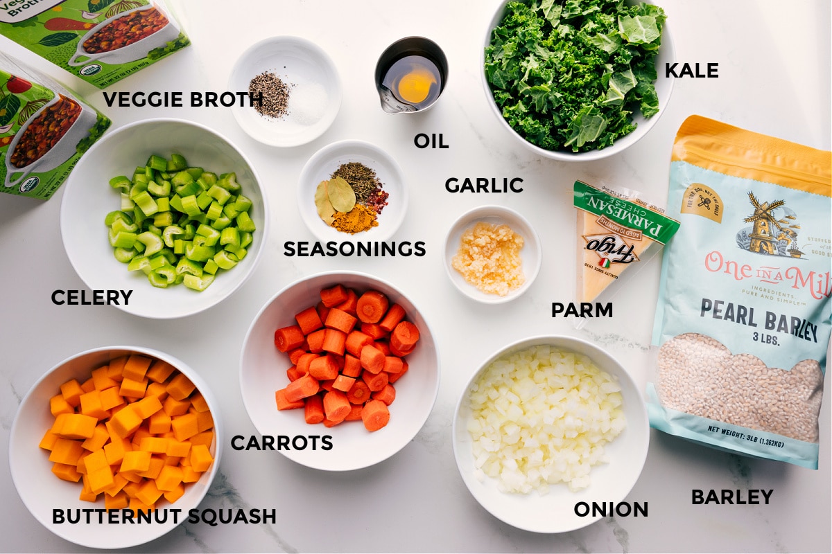 Ingredients In Barley Soup Recipe All the ingredients in this recipe prepped out for easy assembly including the broth, celery, butternut squash, carrots, seasonings, oil, garlic, onion, parmesan, kale, and barley.