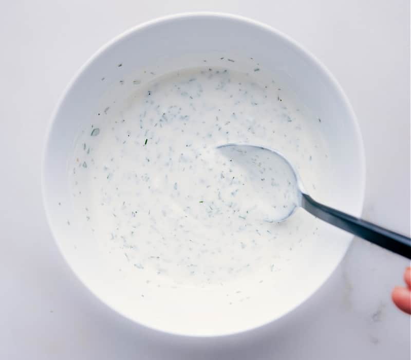 Buttermilk Ranch Dressing Recipe in a bowl with a spoon mixing it up.