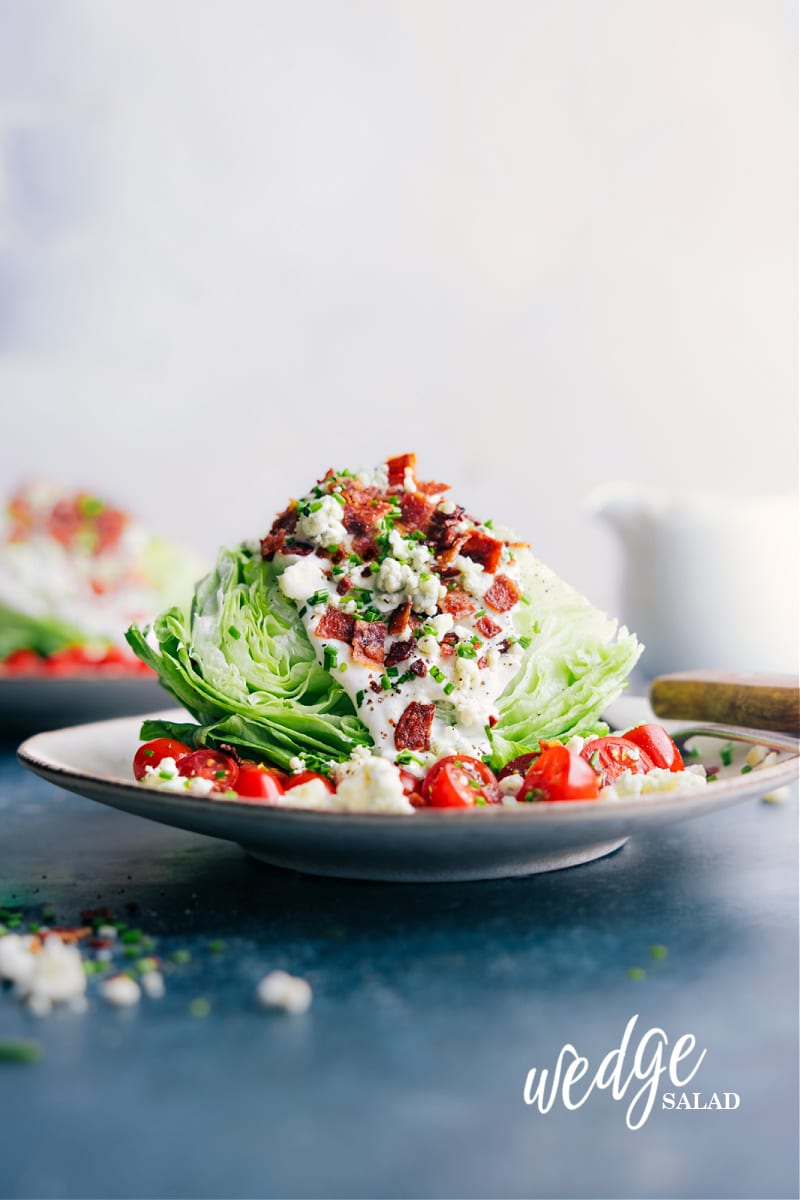 Introducing the ultimate Wedge Salad with the most amazing homemade blue cheese dressing! This classic, crunchy salad is the perfect combination of crisp iceberg lettuce, juicy cherry tomatoes, smoky bacon bits, and topped off with the best homemade blue cheese dressing. This dish is a crowd-pleaser and always a hit at dinner parties and special events. Recipe via chelseasmessyapron #sidedish #best #quick #easy #simple #familyfriendly #kidfriendly #wedgesalad Image of the Wedge Salad ready to be enjoyed