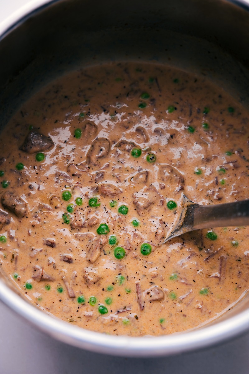 Treat yourself to the ultimate comfort food with this delightful Beef and Noodles recipe. It boasts juicy, tender beef and sweet peas, bathed in a luxuriously rich and flavorful sauce. Enjoy the epitome of coziness, served over egg noodles or mashed potatoes--it's a satisfying meal that you'll crave again and again. Recipe via ChelseasMessyApron.com #beefandnoodles #beef #noodles #chuckroast #roast #creamy #comfortfood #mashedpotatoes #instantpot #slowcooker #crockpot Overhead view of the finished dish