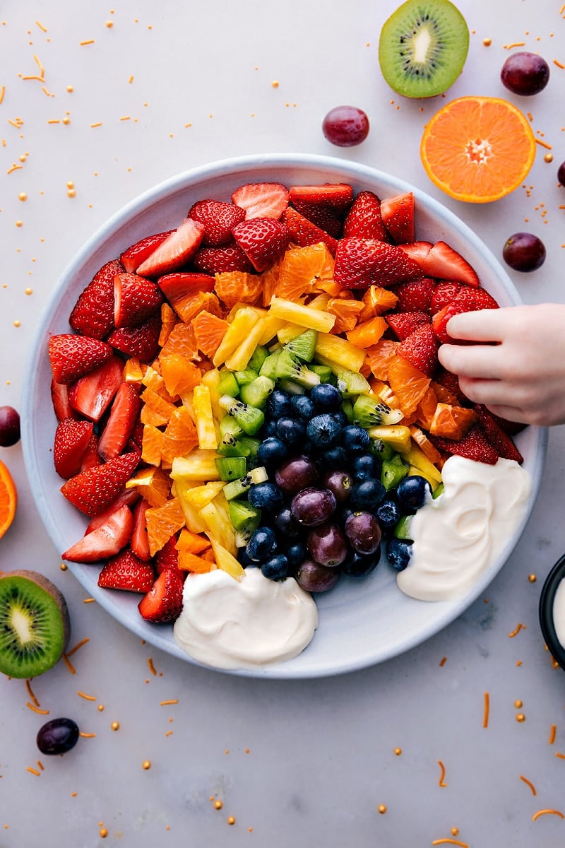 Looking for a fun and colorful way to get your daily dose of fruit? Then you've got to try this amazing Fruit Rainbow Tray with a quick, 3-ingredient Fruit Dip! Perfect for parties, family gatherings, or just a fun snack, this vibrant and delicious tray is sure to brighten up any occasion. Featuring a colorful array of fresh fruits arranged to resemble a rainbow, and a creamy and decadent fruit dip, this recipe is as fun to look at as it is to eat. Recipe via chelseasmessyapron #dessert #best #quick #easy #simple #healthy #wholefoods #cleaneating #fruitdip #dip #fruitraiinbow #tray Overhead image of the Fruit Rainbow Tray
