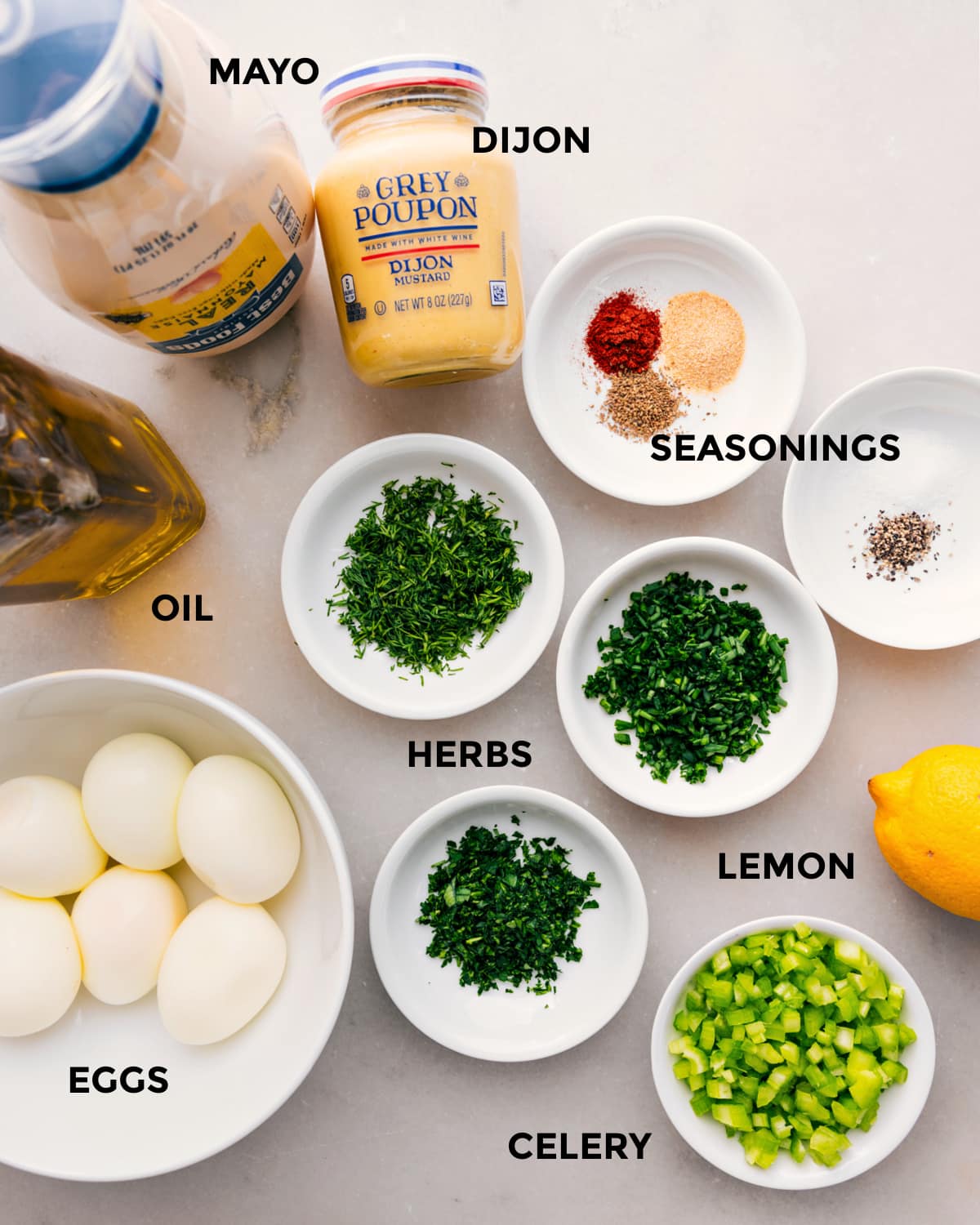 Ingredients In Egg Salad Recipe All the ingredients prepped for easy assembly, including mayo, dijon, seasonings, herbs, oil, eggs, lemon, and celery.