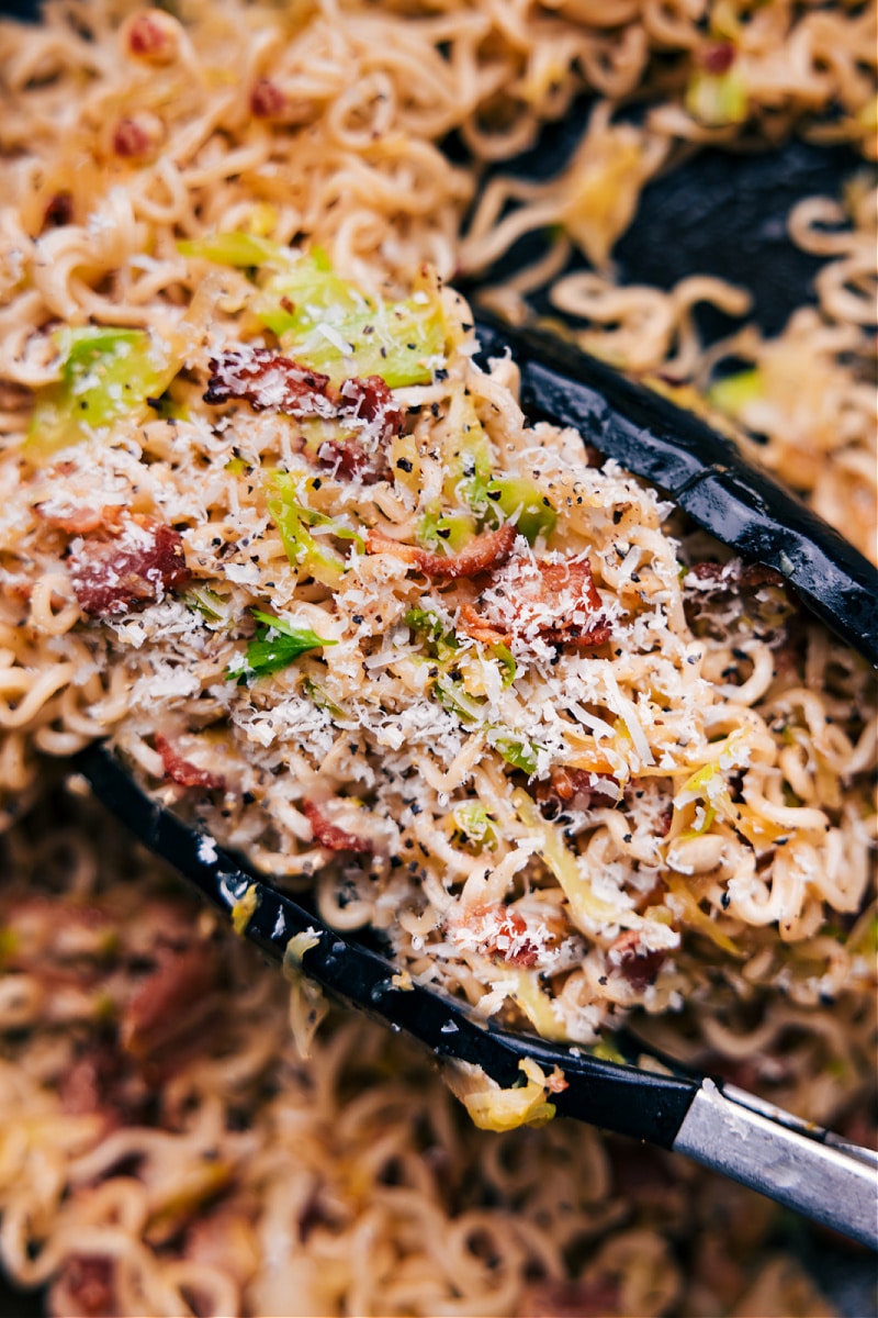 The best Fried Cabbage Ramen recipe! With the addition of smoky bacon, savory onions, and salty parmesan cheese, these noodles are bursting with flavor. This jazzed-up ramen will quickly become a new favorite in your recipe collection! Recipe via chelseasmessyapron #dinner #quick #easy #simple #noodles #asian #stirfry #fried #cabbage #ramen Up-close overhead image of Fried Cabbage Ramen ready to be enjoyed