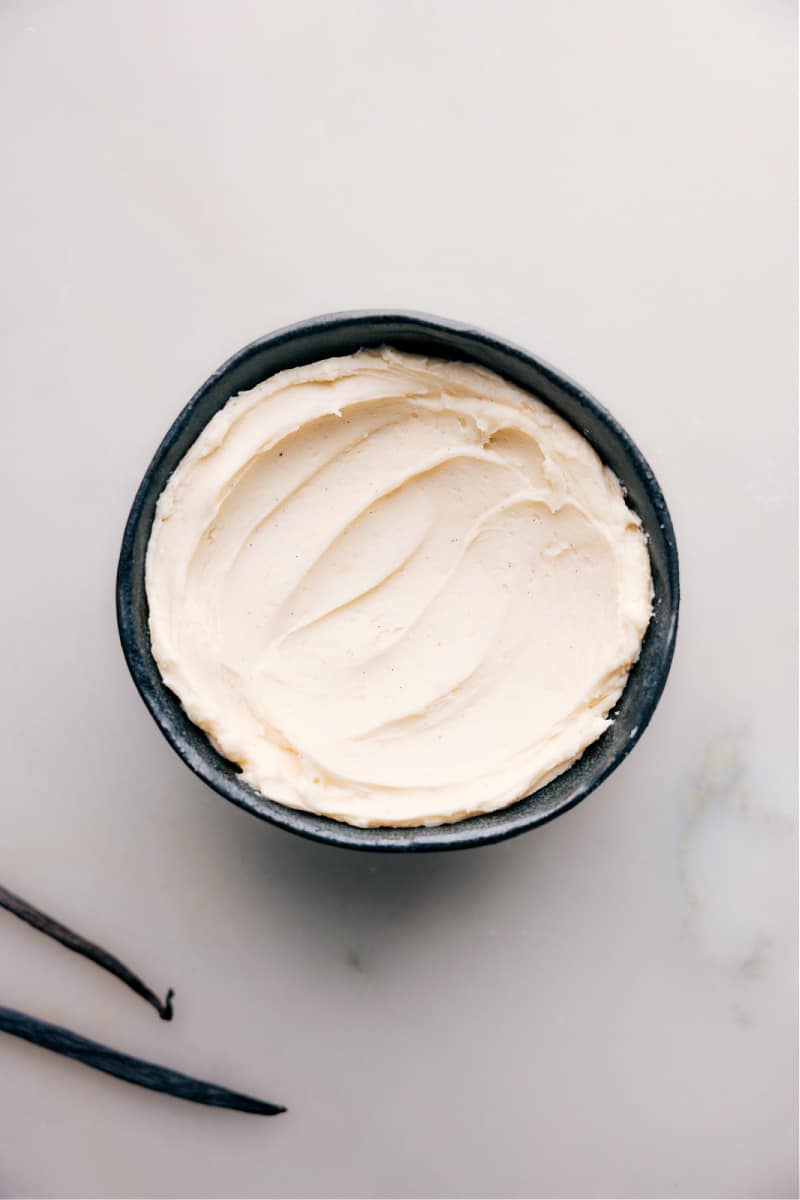 This delicious Vanilla Frosting Recipe is a great, versatile recipe that can be used for all kinds of desserts from cakes and cupcakes to cookies and more. It pairs well with various flavors, such as chocolate, lemon, and strawberry, making it a great all-purpose frosting. Recipe via chelseasmessyapron #dessert #best #quick #easy #simple #familyfriendly #treat #dip #cupcake #cake #vanilla #frosting #vanillafrosting Overhead image of the Vanilla Frosting in a bowl