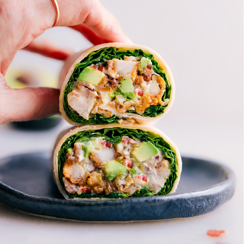 The best Chicken Bacon Avocado Wraps are the perfect quick and easy meal that is packed with flavor! With tender chicken, crispy bacon, creamy avocado, and a completely irresistible sauce, these wraps are incredible! Plus, they're so easy to make that you can whip them up in just a few minutes for a delicious lunch or dinner. Recipe via chelseasmessyapron #dinner #lunch #quick #easy #simple #familyfriendly #kidfriendly #healthy #wholefoods #lunch #chicken #bacon #avocado #tortillawraps #wraps #lunchwraps image of a wrap cut in half stacked