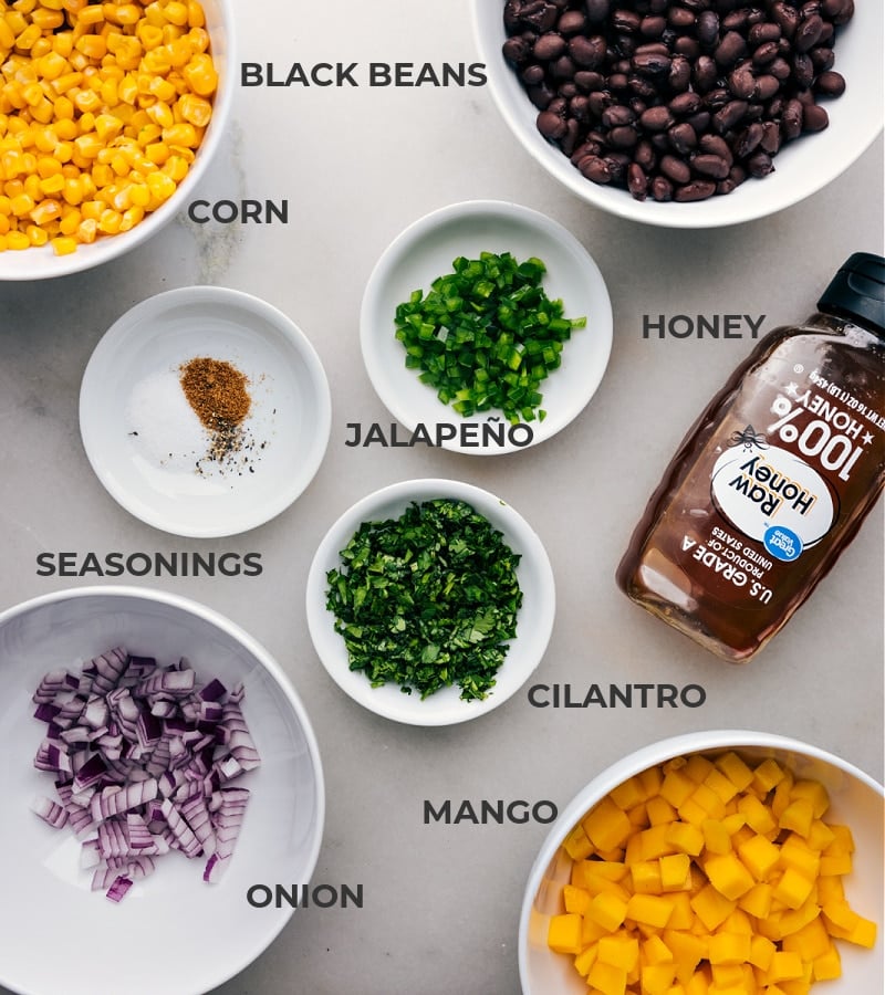 Ingredients In Mango Black Bean Salsa Ingredients in this recipe prepped and ready to go, including beans, corn, honey, jalapeño, seasonings, onion, and fruit.