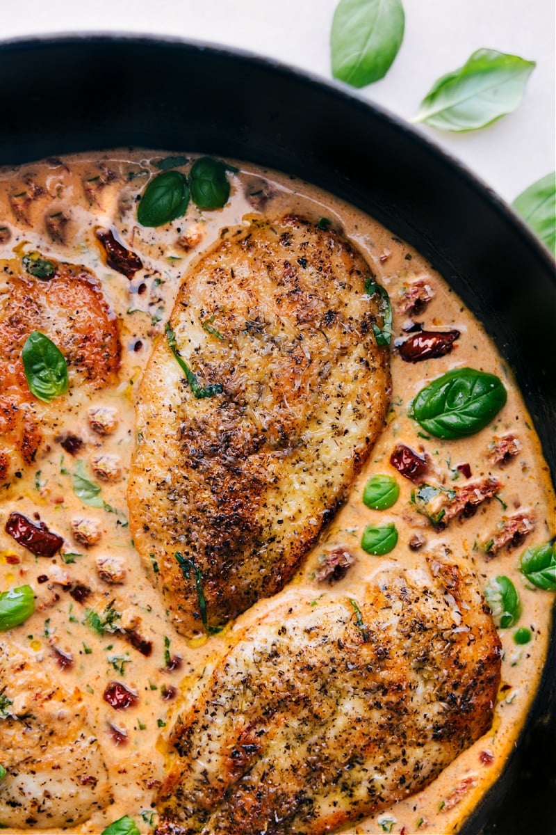 Creamy Marry Me Chicken served in a skillet with sun-dried tomatoes and fresh basil.