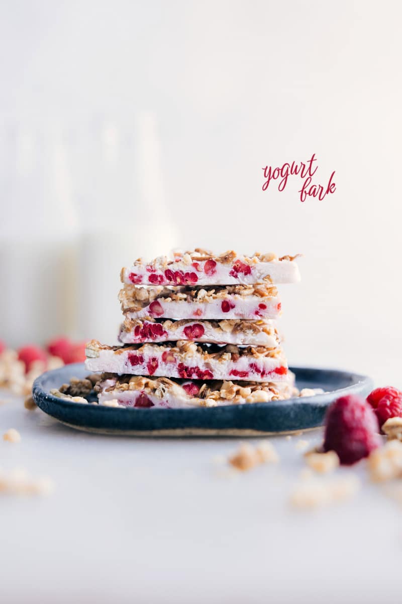 Our utterly irresistible Yogurt Bark features a creamy Greek yogurt and raspberry base, adorned with a medley of your favorite crunchy toppings. It's almost unbelievable that a snack this delicious can also be quite good-for-you! Recipe via chelseasmessyapron #snack #quick #easy #simple #healthy #toddlerfriendly #kidsnack #treat #yogurt #bark Image of Yogurt Bark pieces stacked on top of each other