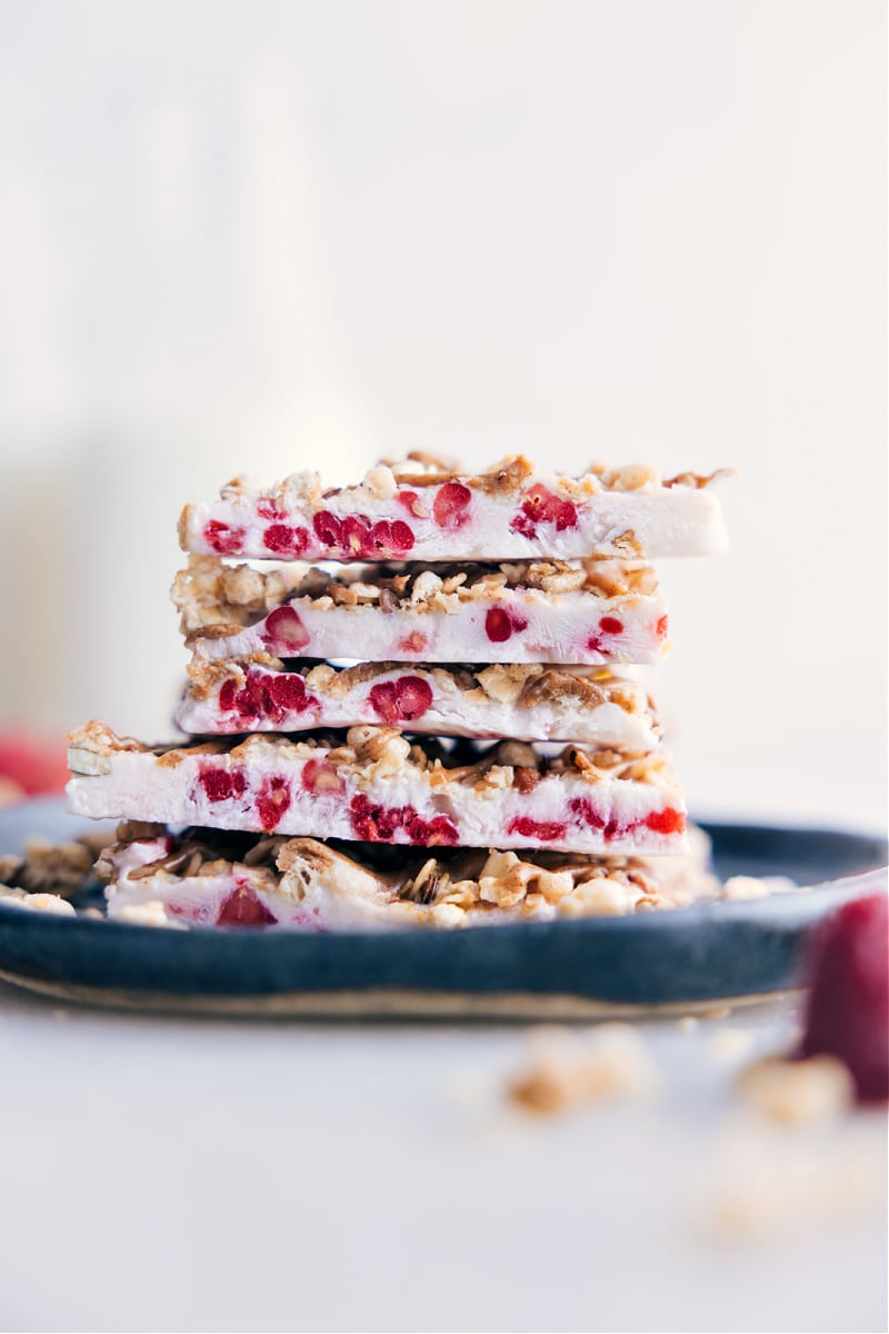 This Yogurt Bark features a creamy Greek yogurt and raspberry base, adorned with a medley of your favorite crunchy toppings. It's almost unbelievable that a snack this delicious can also be quite good-for-you! Recipe via chelseasmessyapron #snack #quick #easy #simple #healthy #toddlerfriendly #kidsnack #treat #yogurt #bark Image of Yogurt Bark pieces stacked on top of each other