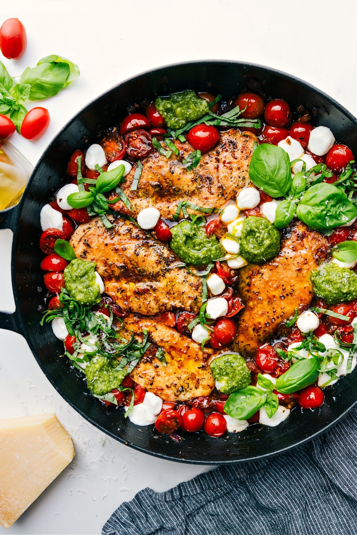 Skillet Caprese chicken with fresh pesto, melted mozzarella, and tomatoes cooked together.