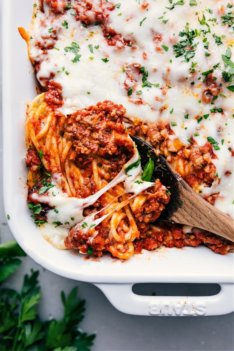 This TikTok Spaghetti is a layered delight with robust flavors - pasta is first tossed in a creamy Alfredo sauce boasting notes of garlic and Parmesan, then topped with a hearty layer of Italian sausage in rich marinara sauce. The dish is crowned with melted mozzarella and Parmesan, resulting in a combination of creamy and savory flavors with a cheesy finish. This dish is perfect for a hearty, satisfying meal. Recipe via chelseasmessyapron #dinner #quick #easy #simple #familyfriendly #kidfriendly #comfortfood #casserole #onepan #tiktok #spaghetti Overhead image of TikTok Spaghetti