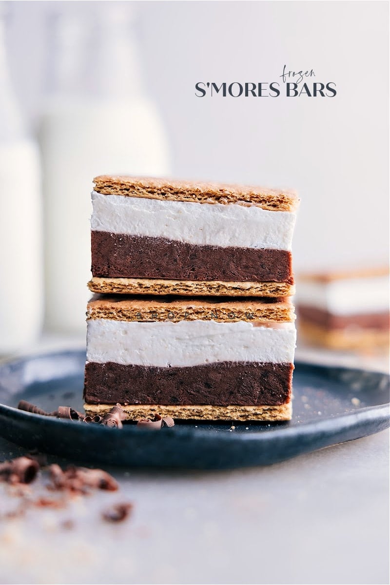 These delicious Frozen S'mores bars combine the rich and creamy flavors of chocolate pudding and whipped topping with the sweet, gooey goodness of marshmallow creme, all sandwiched between crispy honey graham crackers. Recipe via chelseasmessyapron #dessert #nobake #treat #best #summerdessert #frozen #smoresbars #smores Image of the frozen s'mores bars stacked on top of eachother