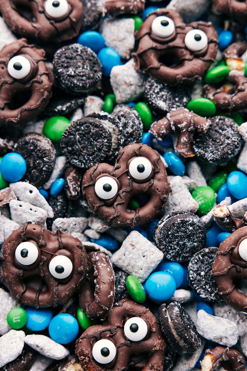 These Goblin Goodies (Halloween Muddy Buddies) are a fun Halloween treat, bursting with rich flavors of chocolate and peanut butter, complemented by the crunch of cereal, Oreos, and M&M's. It's a sPoOky and delicious snack mix you won't want to miss! Recipes via ChelseasMessyApron.com #halloween #oreos #M&Ms #ches #muddybuddies #snackmix. Closeup view of Goblin Goodies