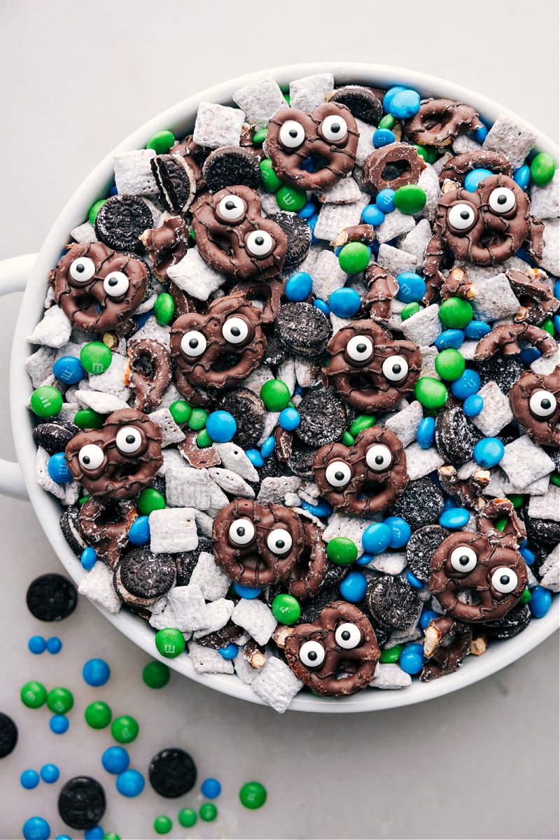 These Goblin Goodies (Halloween Muddy Buddies) are a fun Halloween treat, bursting with rich flavors of chocolate and peanut butter, complemented by the crunch of cereal, Oreos, and M&M's. It's a sPoOky and delicious snack mix you won't want to miss! Recipes via ChelseasMessyApron.com #halloween #oreos #M&Ms #ches #muddybuddies #snackmix Close-up view of Goblin Goodies snack mix