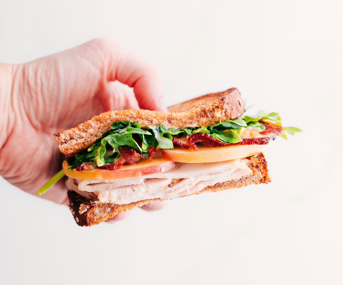 Quick And Easy Turkey And Apple Sandwich Half of the turkey sandwich held up to show the yummy inside.
