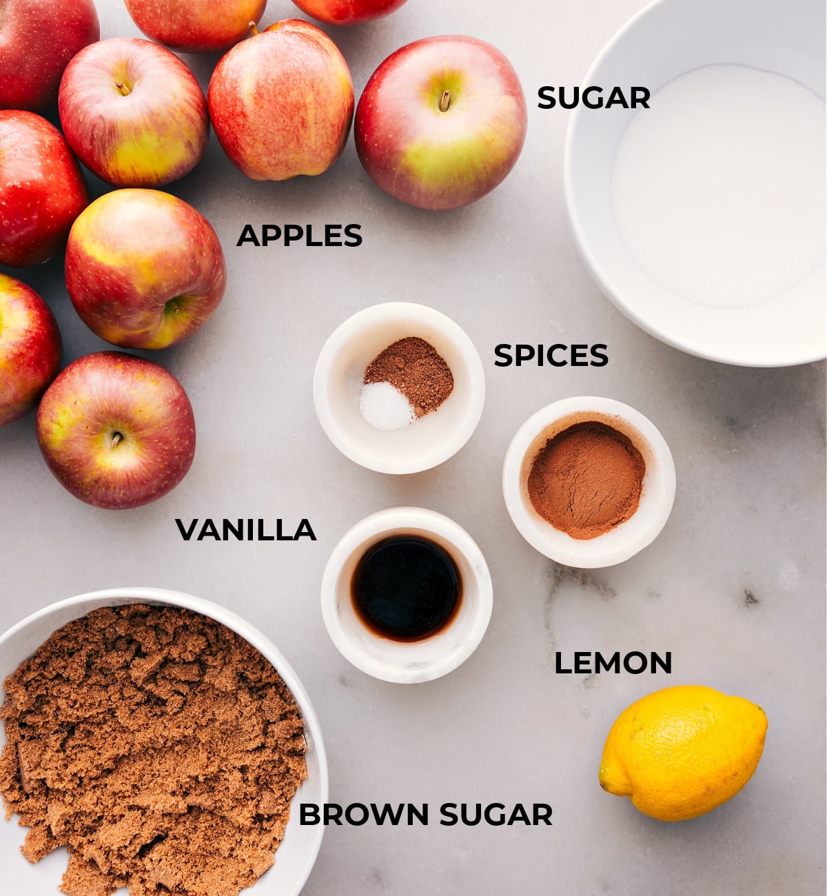 Ingredients In Crockpot Apple Butter Assorted ingredients spread out, including fresh fruits, a mix of spices, vanilla extract, and granulated sugar.