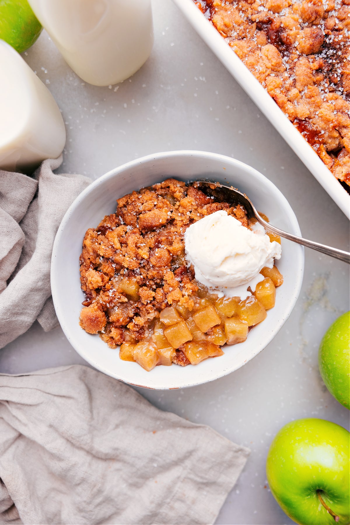 Apple cobbler recipe with a scoop of ice cream in a bowl with a spoon.