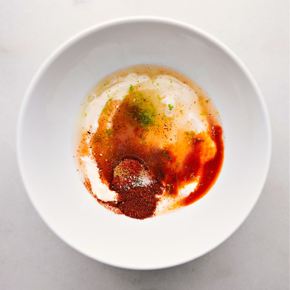Preparing the Perfect Fish Taco Sauce: A Symphony of Ingredients Ingredients for Fish Taco Sauce, including creamy condiments and spices, in a bowl ready for mixing.