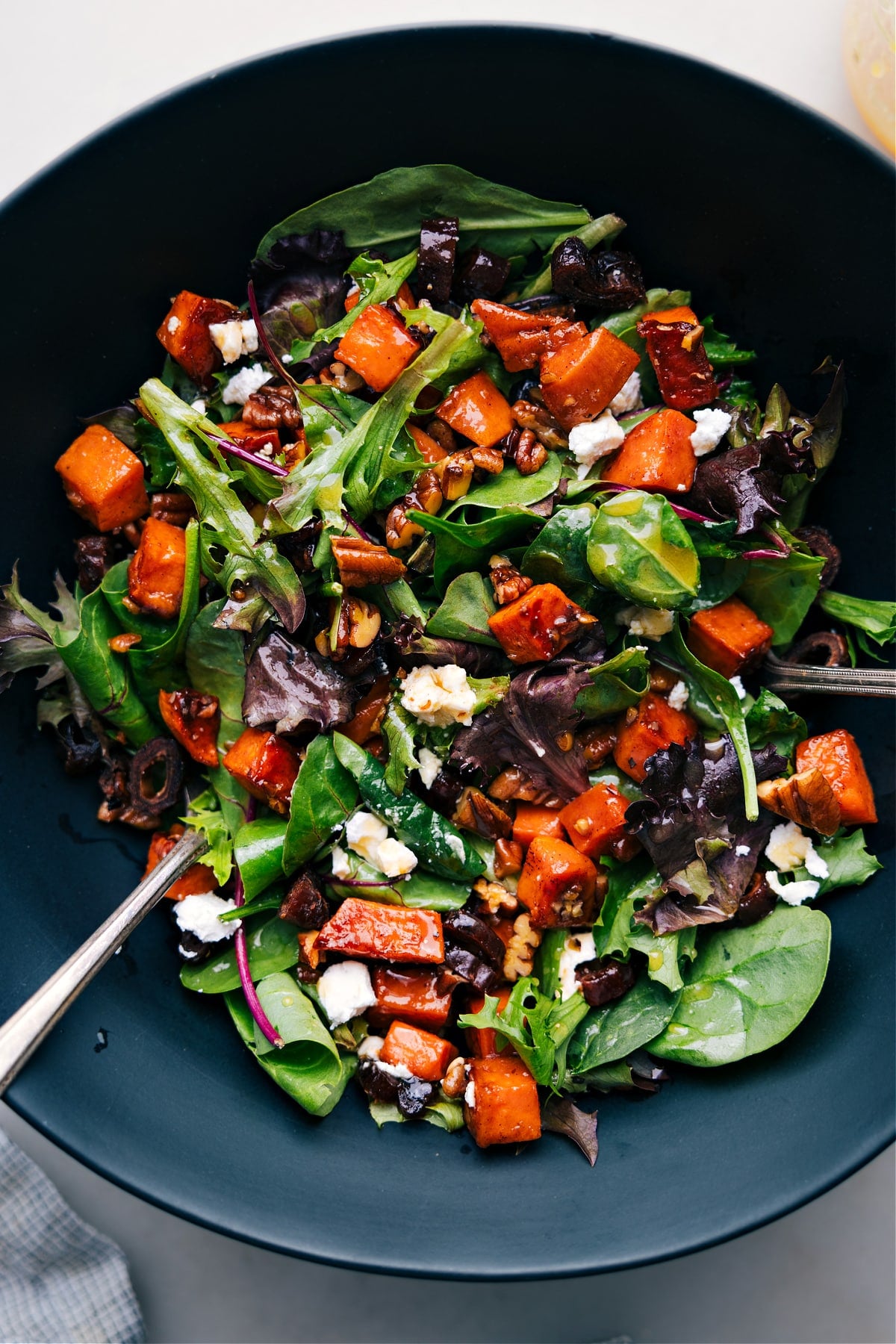 Colorful and Flavorful: Dive into This Delicious Sweet Potato Salad! A vibrant bowl of sweet potato salad, featuring diced roasted sweet potatoes mixed with various colorful ingredients.