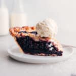 Slice of berry pie with ice cream on top.