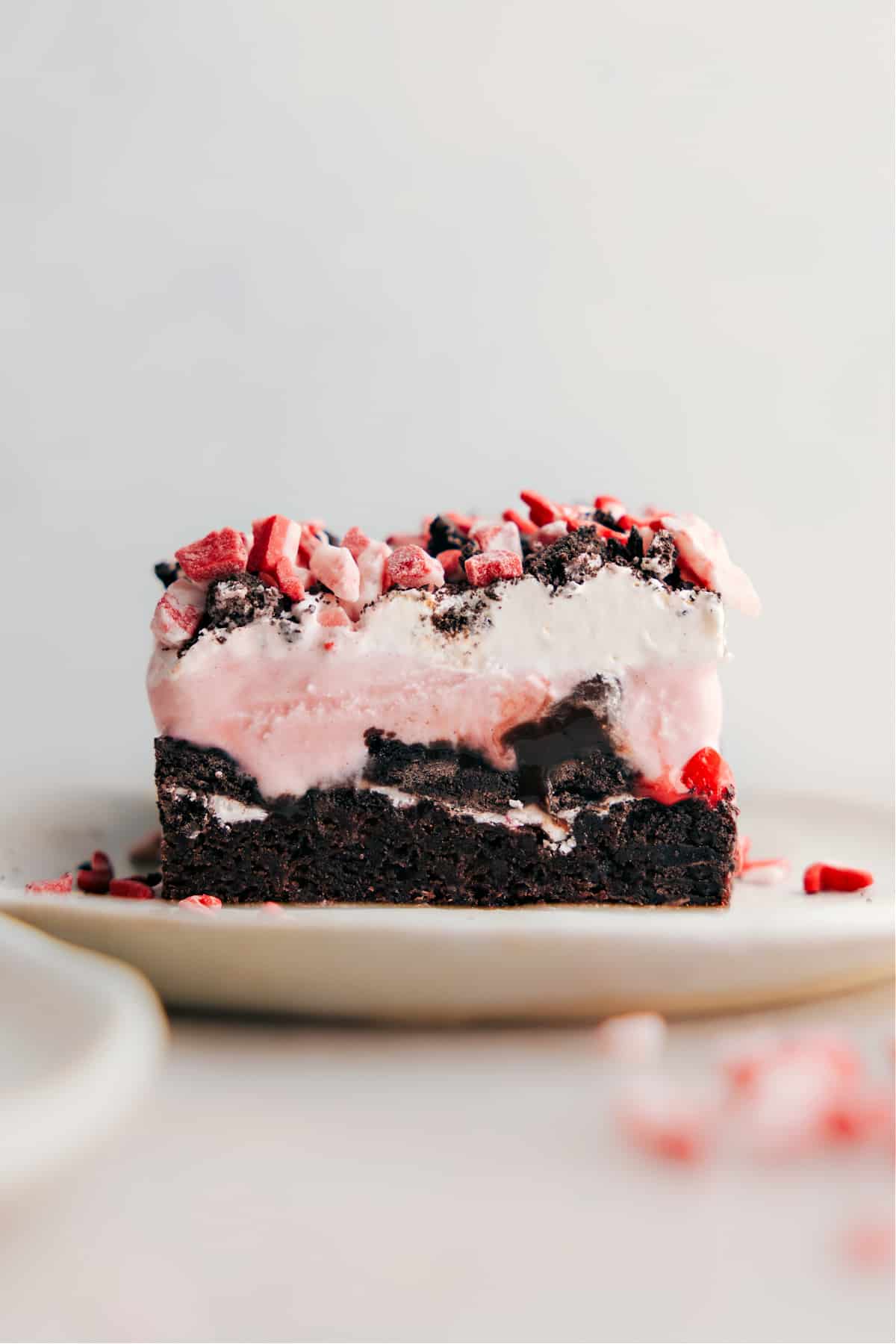 Slice of Peppermint Brownie Ice Cream Bar A slice of Peppermint Brownie Ice Cream Bar, displaying its stunning layers with a rich brownie base, a thick layer of ice cream, and a topping of crushed peppermint, exemplifying a perfect blend of textures and flavors.
