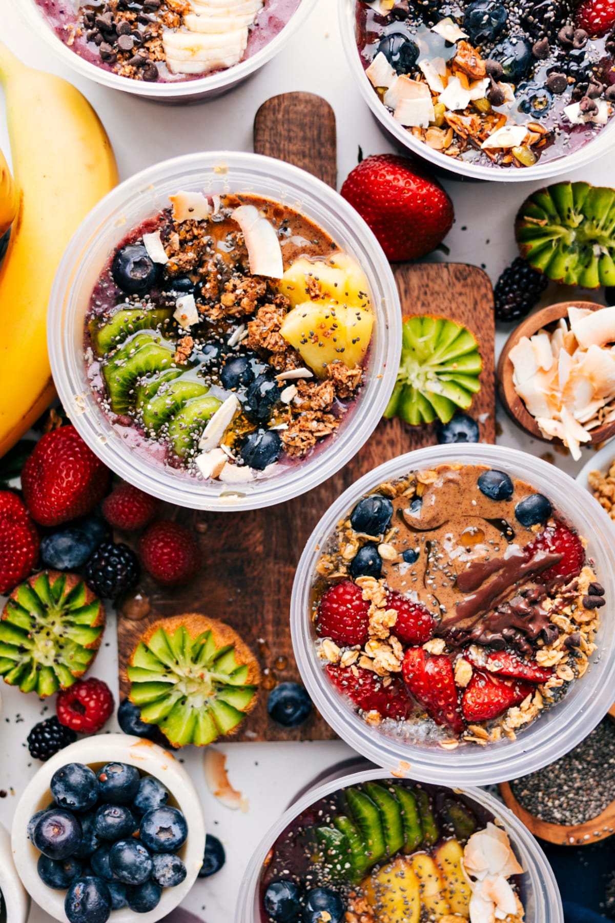 Acai bowls recipe with a variety of toppings spread out on a counter.