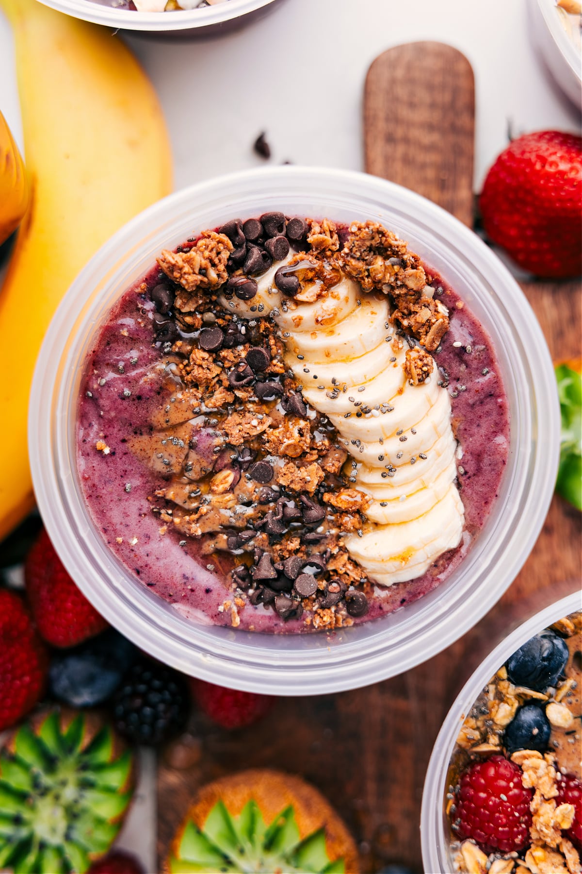 Chocolate Peanut Butter Acai Bowls Recipe Peanut butter chocolate smoothie bowl topped with granola, bananas, peanut butter, chocolate chips, and honey.