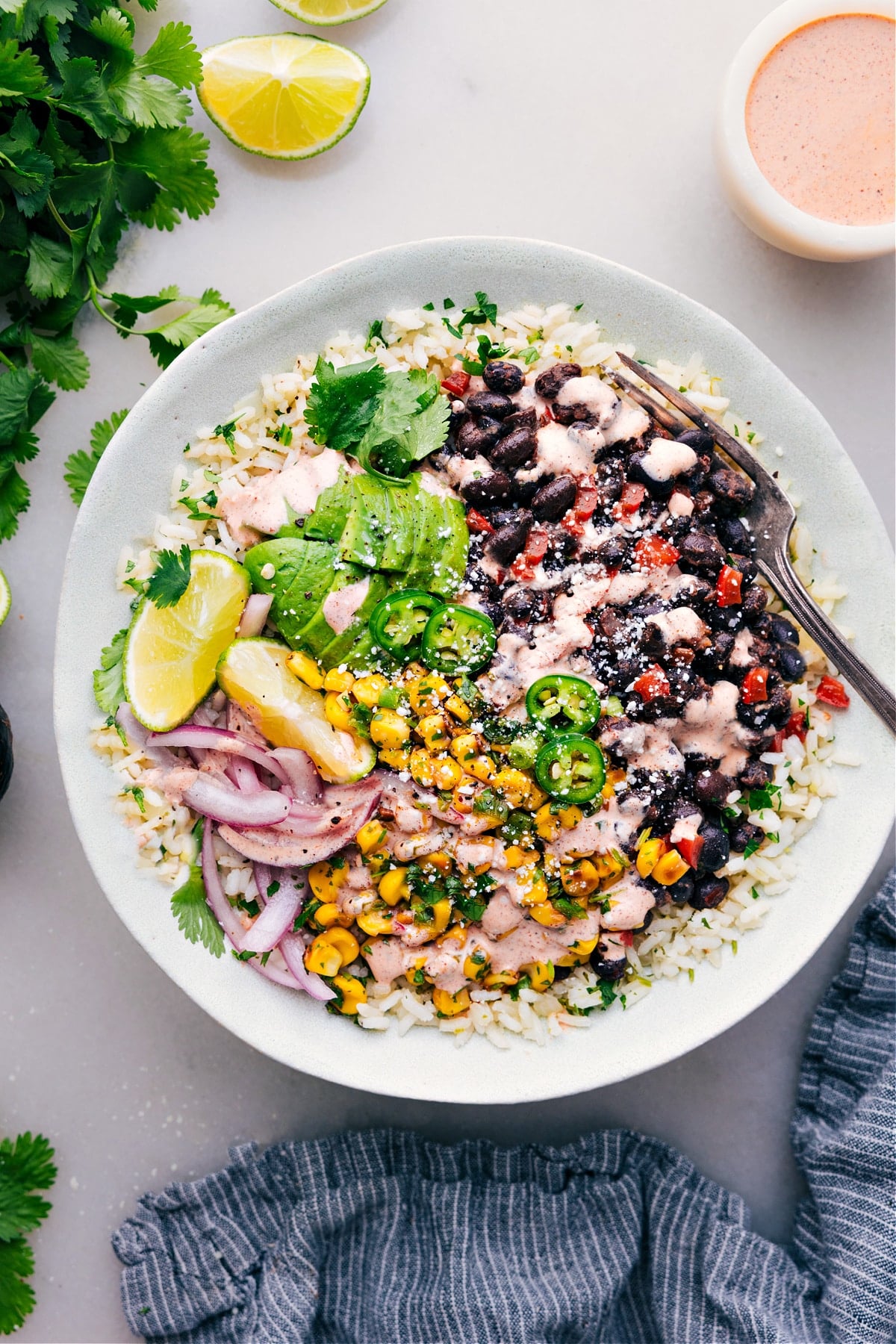 Black Bean Burrito Bowl Black bean burrito bowl with creamy sauce, rice, beans, and fresh toppings in a bowl.