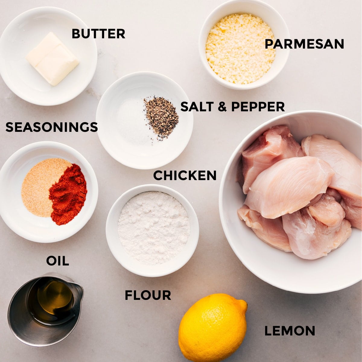 Ingredients In The Best Chicken Cutlets Recipe All the ingredients for this recipe are prepped and ready for easy assembly: parmesan, seasonings, chicken, flour, oil, and a lemon.