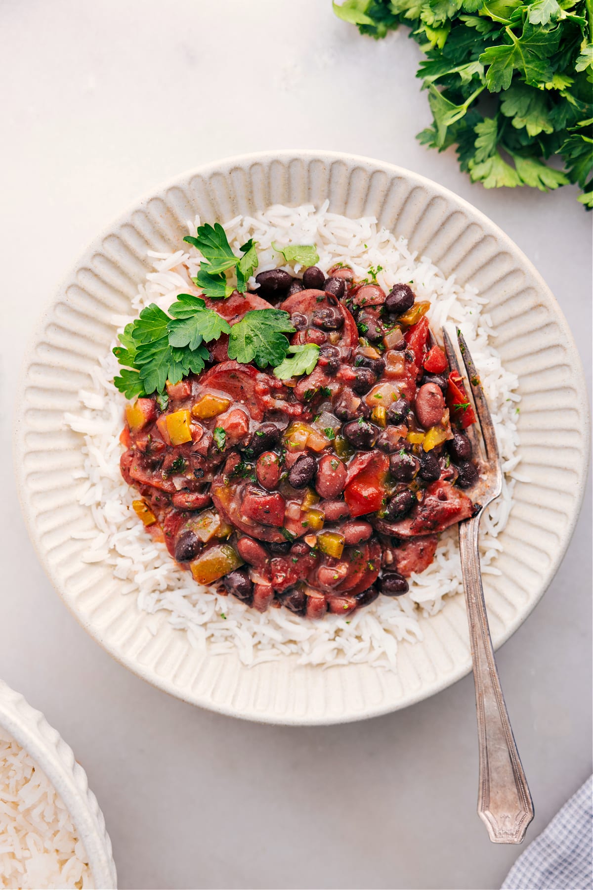 Serve Slow Cooked Black Beans And Sausage Over Rice Black beans and sausage over rice with fresh herbs on top.