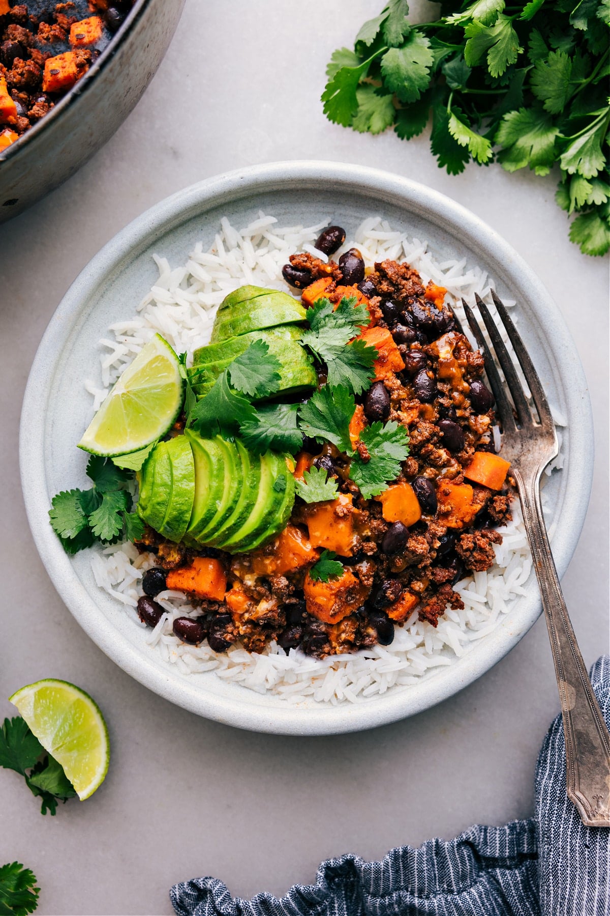 Ground Turkey Sweet Potato All Made In One Skillet Ground Turkey Sweet Potato Skillet served on a plate of rice with fresh avocado, cilantro, and lime on the side.