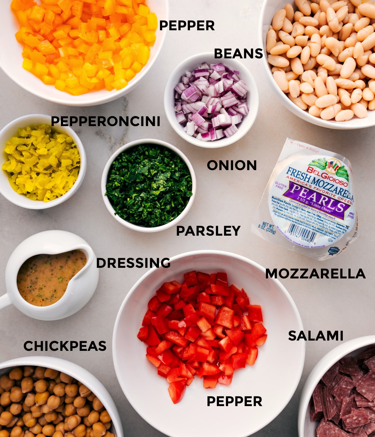 Ingredients In Dense Bean Salad Recipe All the ingredients for this recipe are prepped and ready for easy assembly: beans, onion, parsley, mozzarella, pepper salami, pepperoncini, chickpeas, and dressing.