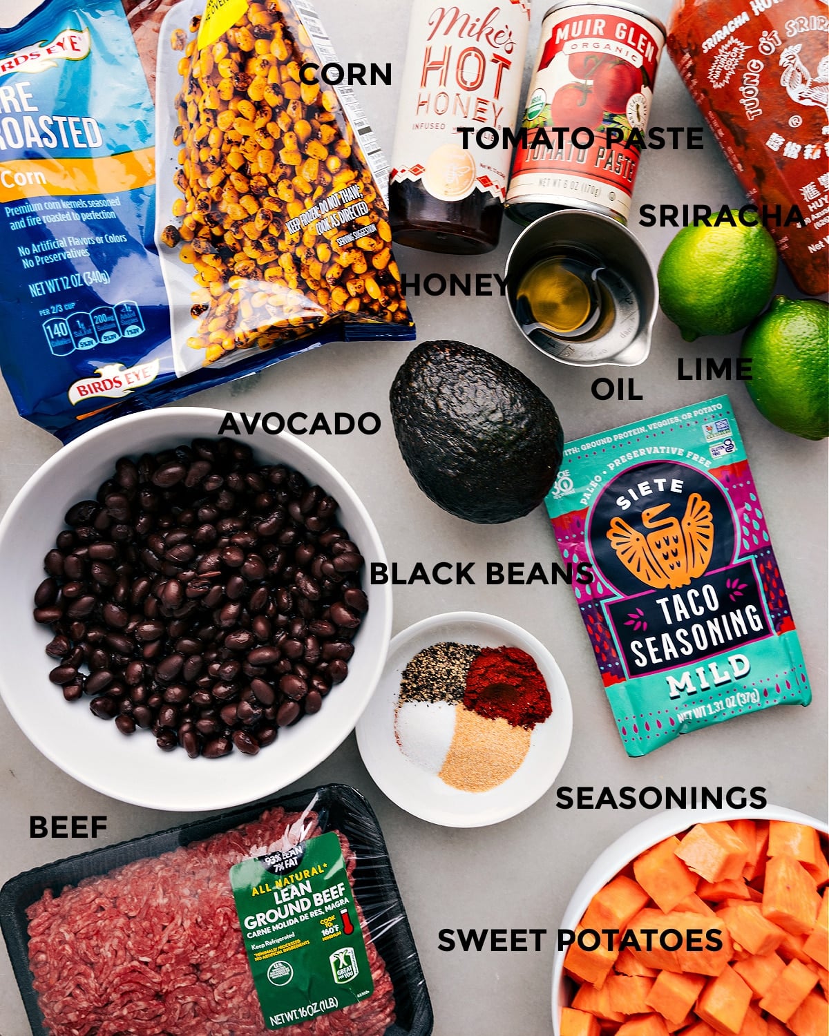 Ingredients In Ground Beef Taco Bowl All the ingredients for this recipe are prepped and ready for easy assembly, including corn, hot honey, tomato paste, sriracha, lime, oil, avocado, seasonings, black beans, meat, and sweet potatoes.