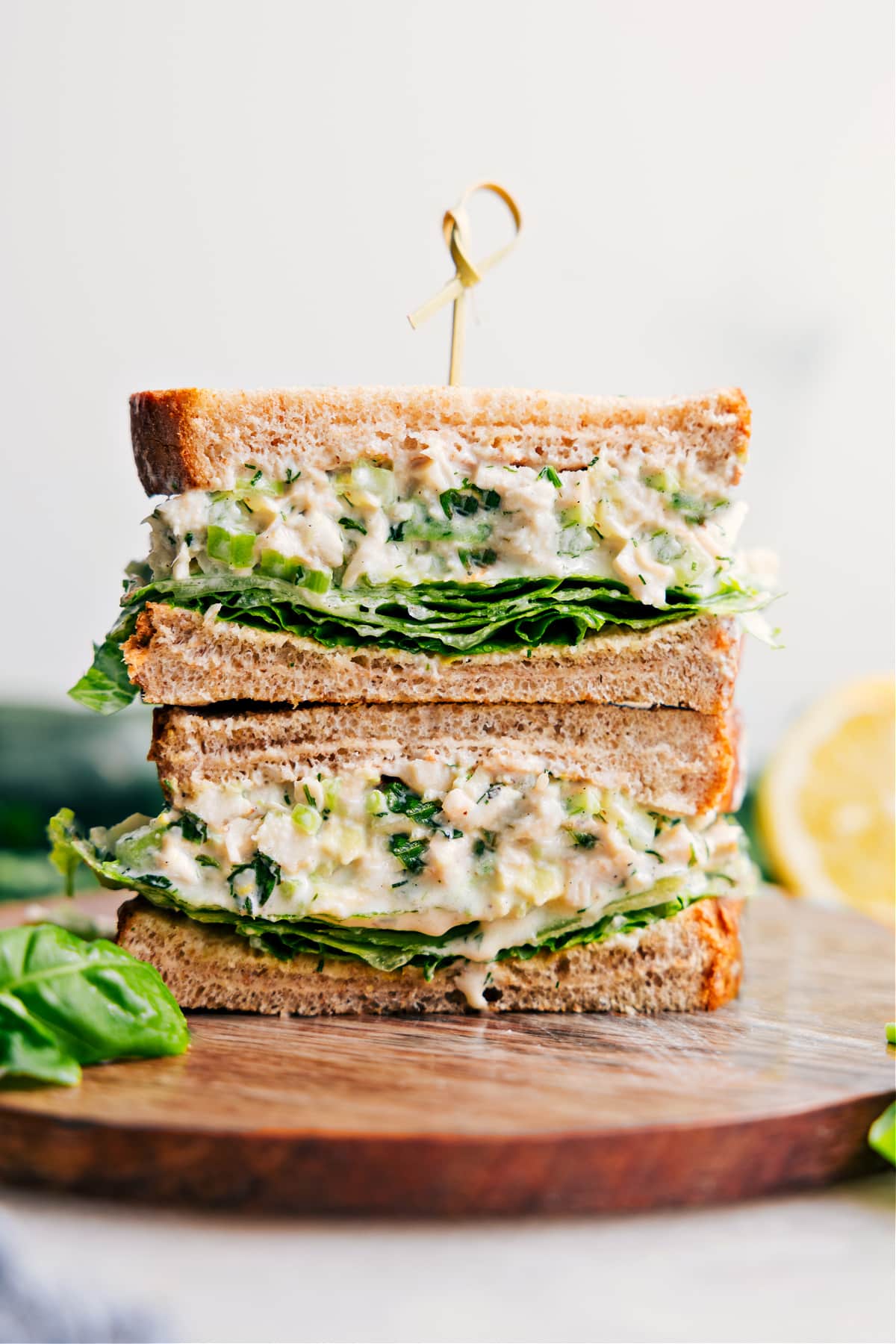 Lemon Basil Chicken Salad Recipe Lemon-Basil Chicken Salad in bread makes a sandwich, with the sandwich cut in half and stacked on top of each other.